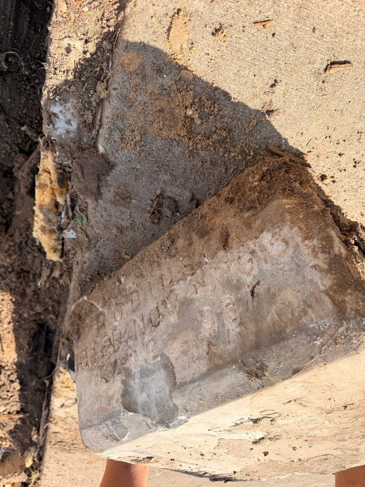 Hand-cut lettering on a partially buried stone