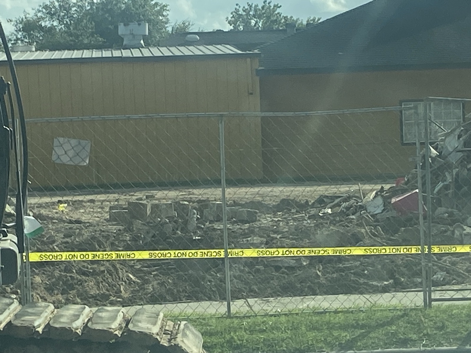 Crime-scene tape strung across the fenced demolition site
