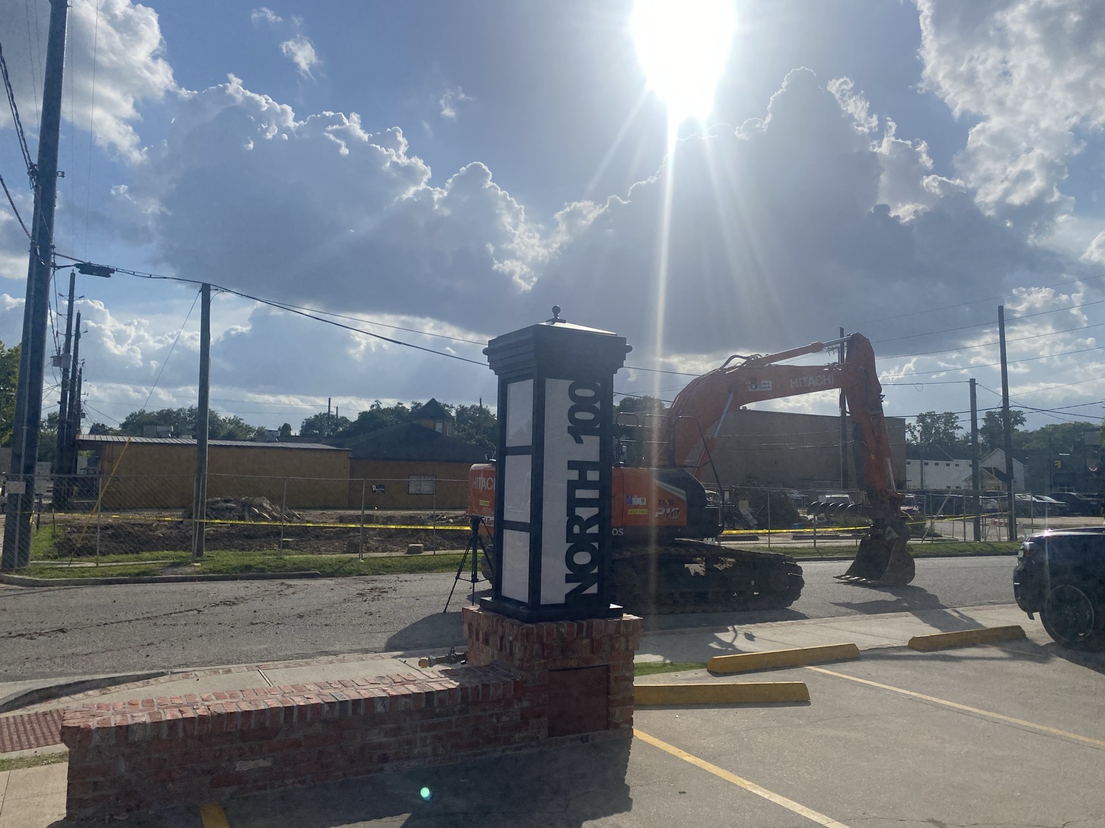 The North 100 marker with an excavator behind the fenced site