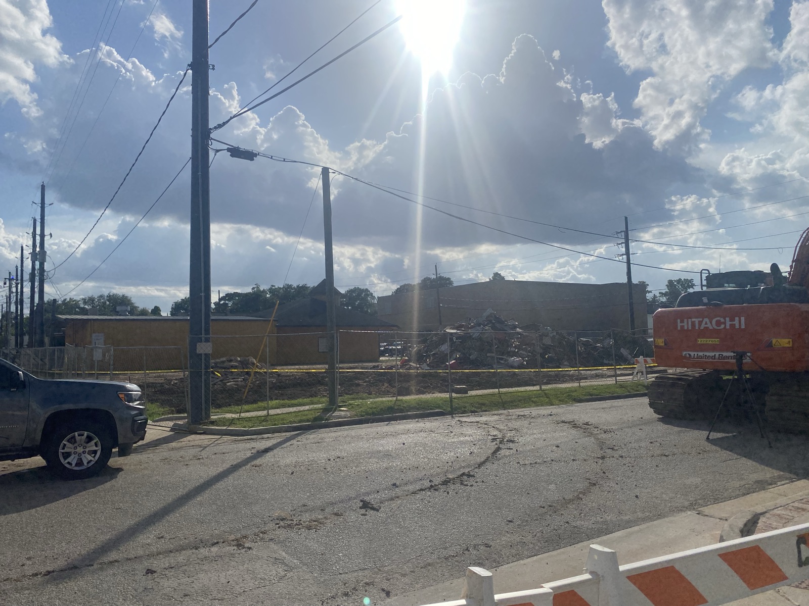Rubble pile and excavator behind construction fencing